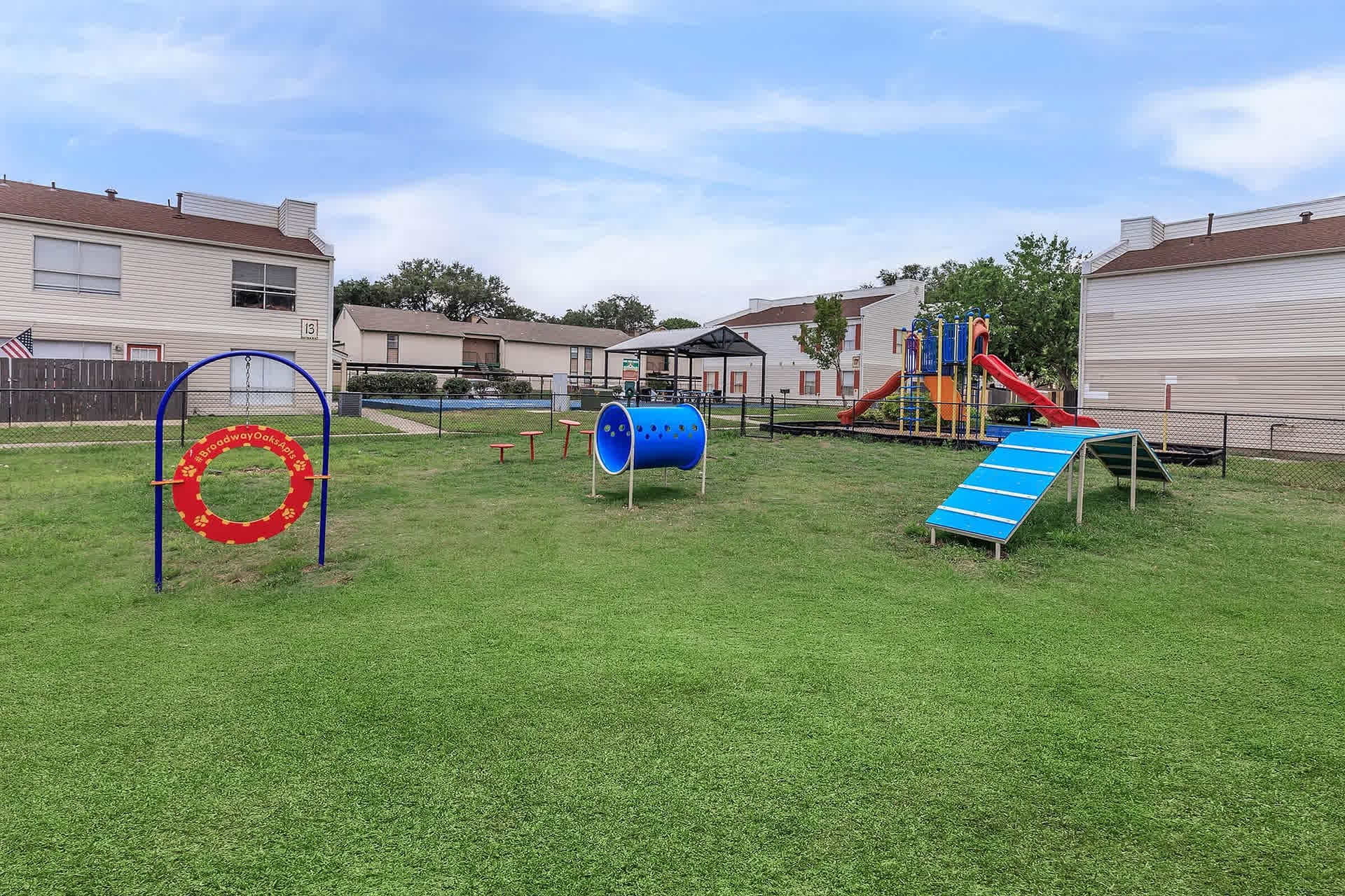 Fenced dog park and lawn with apartment buildings behind