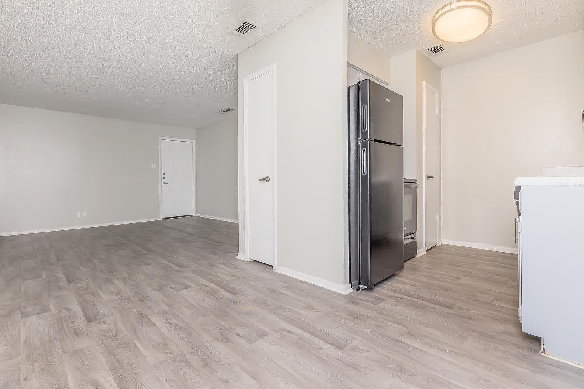 Empty open-plan living room and kitchen with wood-look floors